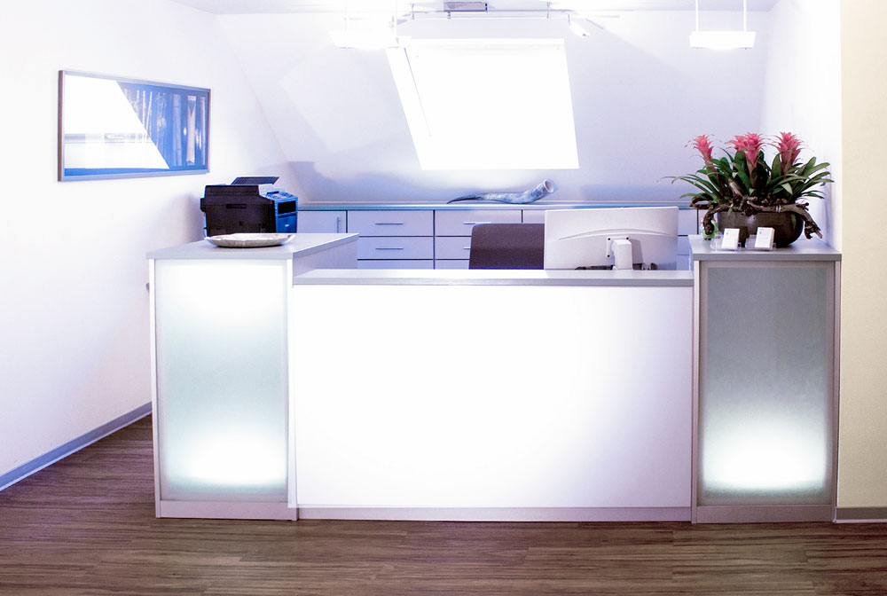 Behandlungszimmer der Zahnarztpraxis Dirk Alda in Niederkassel bei Bonn, mit Holzfussboden, hochwertiger technischer Einrichtung, warmen Farben und Flatscreen.