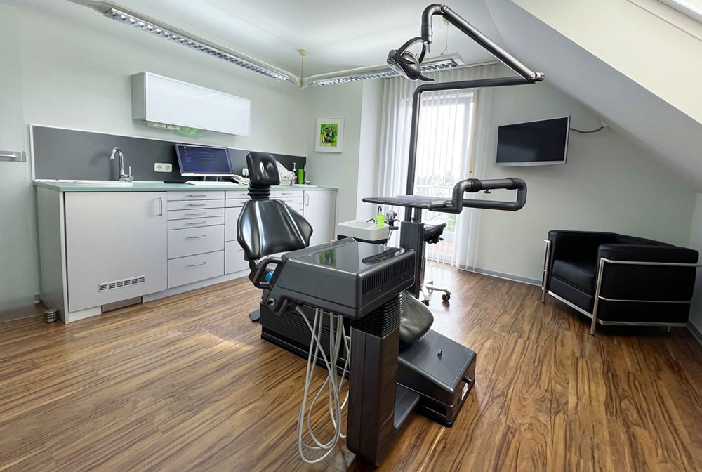 WWartezimmer der Zahnarztpraxis Dirk Alda in Niederkassel bei Bonn, mit Holzfussboden, hochwertiger Einrichtung, warmen Farben, Flatscreen und fröhlicher Kunst an den Wänden.